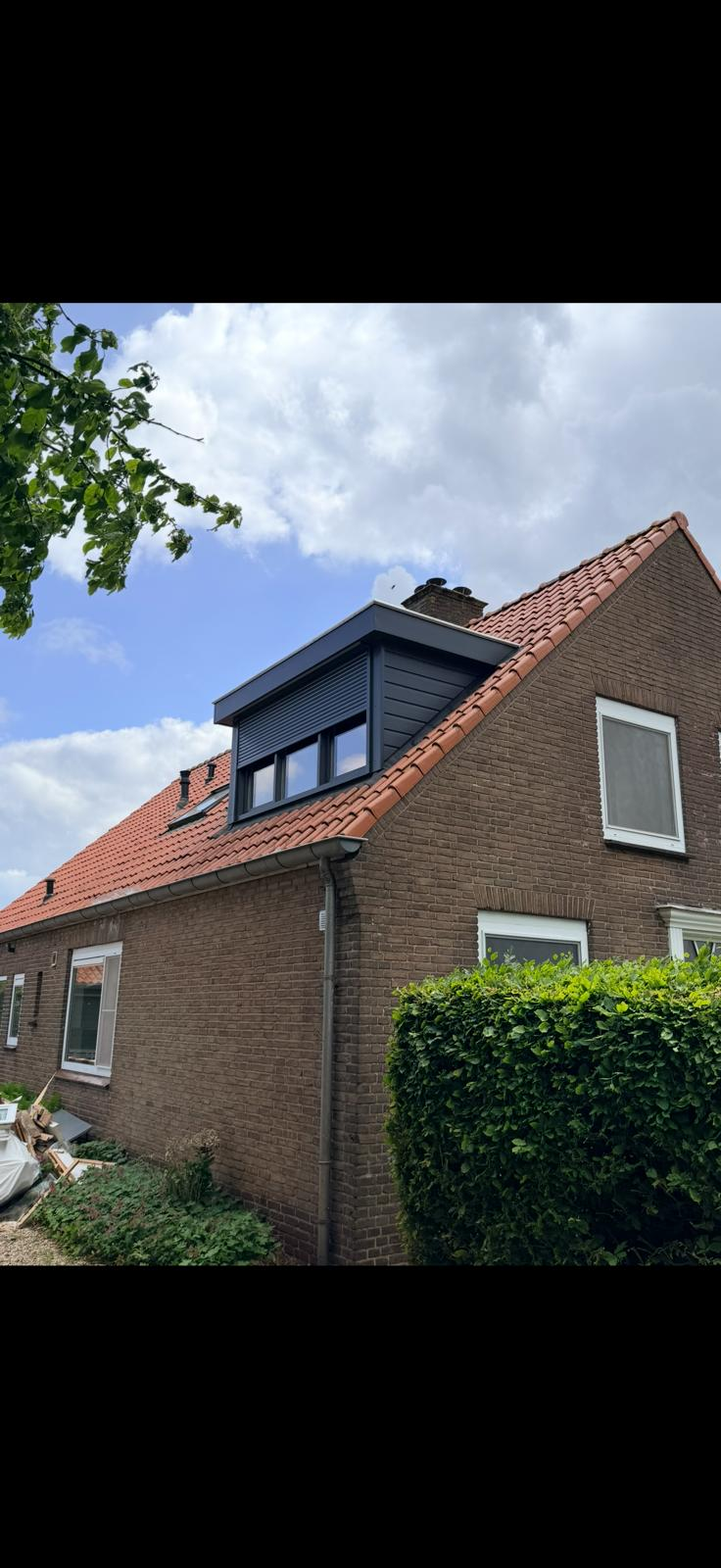 Donkergrijze dakkapel op een woning met pannendak